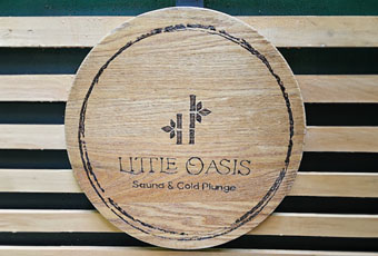 A circular piece of timber with the Little Oasis logo etched into it.