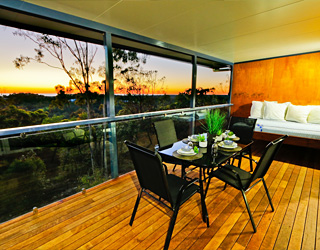 Verandah with table and chairs and a view of the sunset.